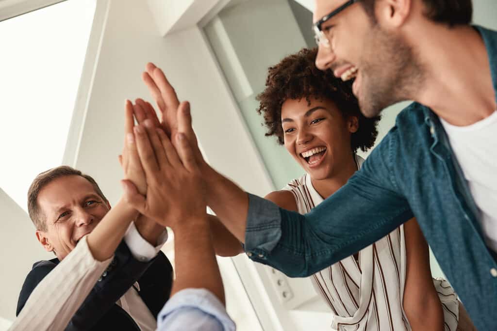 Celebrating success. Business people giving each other high-five and smiling while working together
